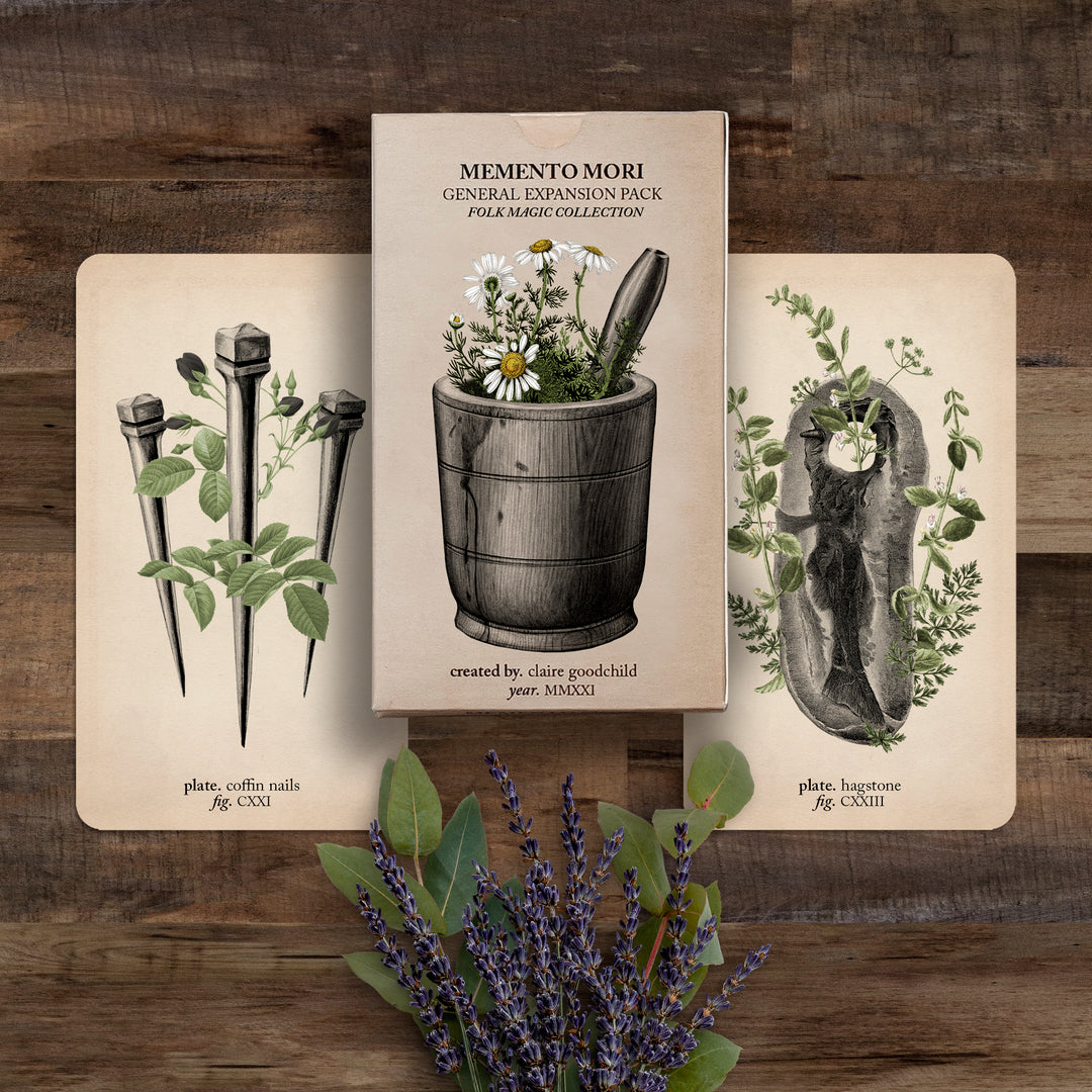 The Folk Magic expansion pack and two cards (coffin nails and hagstone) against a wooden background with lavender flowers below